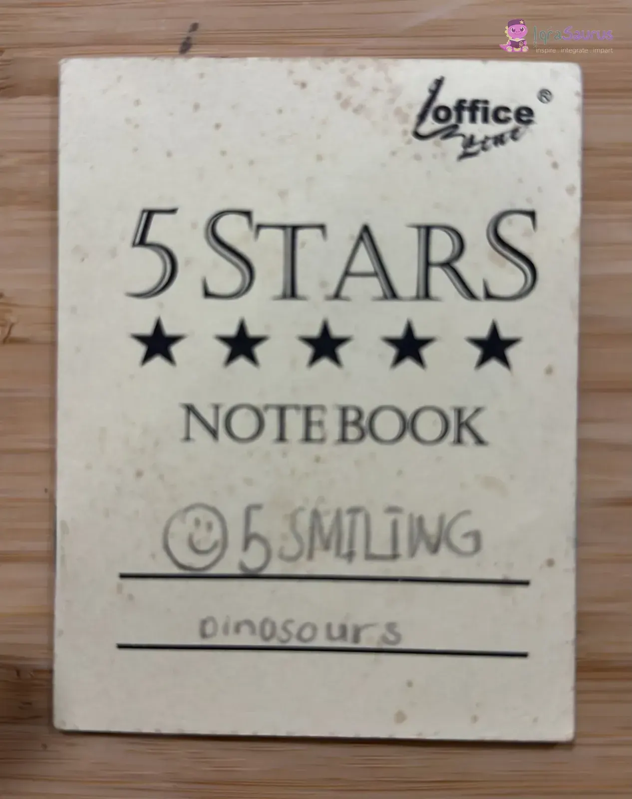 The small notebook cover with a smiley face and the title written by hand.