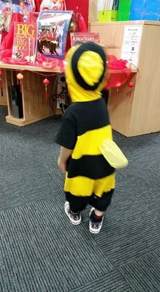 Qoyis, seen from behind, in a bee costume at the library