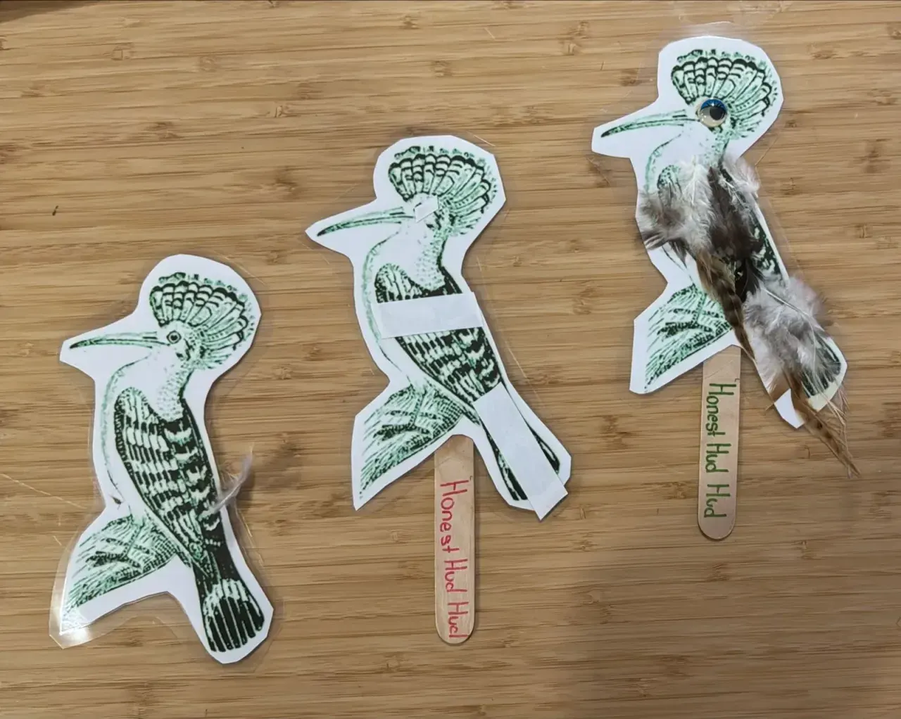 Three hoopoe puppets at different stages: plain, with tape, and finished with feathers and an eye